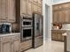Modern kitchen with stainless steel appliances, custom cabinets, and tiled flooring at 8271 Redonda Loop, Lakewood Ranch, FL 34202