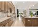Long kitchen with wood cabinetry, granite counters, and an island with a sink at 8271 Redonda Loop, Lakewood Ranch, FL 34202