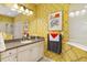 Charming bathroom with yellow patterned walls, a large mirror and a vanity with a sink at 12019 Sawgrass Lake Ter, Bradenton, FL 34211