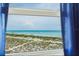 Picturesque ocean view from the window, showcasing the calming sea and sandy dunes, framed by blue curtains at 1255 Tarpon Center Dr # 315, Venice, FL 34285