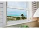 A window with shutters provides a view of the beach and palm trees at 1255 Tarpon Center Dr # 315, Venice, FL 34285