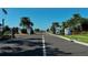 Paved road leading into the community entrance with security gate, palm trees and manicured greenery at 13540 Old Creek Ct, Parrish, FL 34219