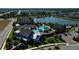 An aerial view showcases a clubhouse with a luxurious pool area surrounded by palm trees and a lake at 13540 Old Creek Ct, Parrish, FL 34219