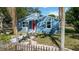 Charming blue home with a bright red front door, surrounded by a quaint picket fence at 1367 21St St, Sarasota, FL 34234