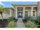 Elegant front entrance with a blue door, columns, decorative windows, and manicured landscaping at 14730 1St E Ave, Bradenton, FL 34212