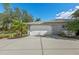 View of the two-car garage with a concrete driveway and tropical landscaping at 14730 1St E Ave, Bradenton, FL 34212