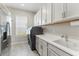 Bright laundry room with modern appliances, white shaker cabinets, and tile flooring at 14803 Derna Ter, Bradenton, FL 34211