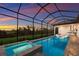 Screened-in pool with jacuzzi and lounge chairs, outdoor kitchen and a view of the sunset at 14803 Derna Ter, Bradenton, FL 34211