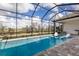 Screened-in pool with jacuzzi and lounge chairs surrounded by brick with a view of the yard at 14803 Derna Ter, Bradenton, FL 34211