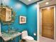 Stylish powder room with a unique glass sink, decorative mirror, and vibrant teal walls at 2141 Gulf Of Mexico Dr Unit # 4, Longboat Key, FL 34228