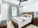 Bedroom boasts a ceiling fan, a classic wooden bed frame, and a large window covered with elegant gray curtains at 2186 Yalta Ter, North Port, FL 34286