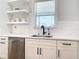 Bright kitchen shows a stainless dishwasher, subway tile backsplash, floating shelves, and black faucet at 2186 Yalta Ter, North Port, FL 34286
