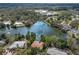 Wide aerial view of a home with a private pool on a lake, surrounded by lush trees, and the cityscape beyond at 326 E Lake Dr, Sarasota, FL 34232