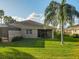 View of the backyard featuring a well-maintained lawn and mature palm tree, and the screened lanai of the house at 375 Fairway Isles Ln, Bradenton, FL 34212