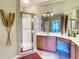 Bathroom featuring tile floors, double sinks, shower with glass door, red rug, and neutral color scheme at 375 Fairway Isles Ln, Bradenton, FL 34212