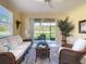 Comfortable sunroom with wicker seating and a serene view of the lush landscaping outside the sliding glass doors at 375 Fairway Isles Ln, Bradenton, FL 34212