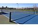 Outdoor tennis court featuring a blue playing surface, black net, and fenced perimeter at 375 Fairway Isles Ln, Bradenton, FL 34212