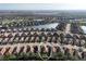 Expansive aerial view of a residential neighborhood with picturesque landscaping, a central lake, and a golf course in the distance at 5020 Savona Run, Bradenton, FL 34211