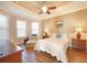 Cozy main bedroom with a tray ceiling, ceiling fan, and an accent chair at 5020 Savona Run, Bradenton, FL 34211