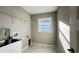 Bright laundry room with a utility sink, white cabinets, and modern white wire shelving at 16491 Volkerts Ave, Port Charlotte, FL 33954