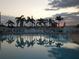 Community pool with palm trees, lounge chairs, and a calming reflection of the sunset at 1750 Palm Springs St, Sarasota, FL 34234