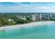 Stunning aerial view of a beachfront condo, a white sand beach, and turquoise water, surrounded by lush landscaping at 231 Hourglass Way # V5, Sarasota, FL 34242