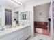 Bright bathroom with double sinks, large mirror and separate pink tiled bathtub at 2376 Novus St, Sarasota, FL 34237