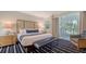 Beautiful bedroom with a plush bed, striped rug, and access to a balcony at 250 Sands Point Rd # 5101, Longboat Key, FL 34228