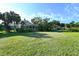 Sprawling lawn showcasing the pool and screened enclosure with tropical plants and a clear blue sky at 2812 Casey Key Rd, Nokomis, FL 34275