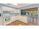 Bright kitchen featuring white cabinets, a microwave, a stove, and a stainless steel sink, with views to an enclosed patio at 2812 Casey Key Rd, Nokomis, FL 34275