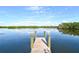 Calm waterfront view from a wooden dock, highlighted by a clear blue sky and lush green shoreline at 2812 Casey Key Rd, Nokomis, FL 34275