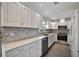 Modern kitchen featuring white cabinetry, stainless steel appliances, mosaic backsplash, and quartz countertops at 5115 Island Date Way, Sarasota, FL 34232