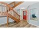 Bright foyer with wood staircase, red front door and wood-look floors create an inviting entrance at 6145 Bonaventure Ct, Sarasota, FL 34243