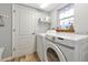 Laundry room with white washer and dryer, storage shelves, and a window at 6145 Bonaventure Ct, Sarasota, FL 34243