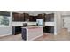 Modern kitchen featuring dark cabinets, stainless steel appliances, and a marble island at 6634 Calypso Coral Ln, Sarasota, FL 34240