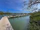 Wooden dock on the water with boat and scenic views of lush greenery under a bright blue sky at 6701 Gulf Of Mexico Dr # 311, Longboat Key, FL 34228