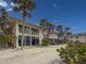Beach condo exterior with second story balcony and patio featuring lush landscaping and palm trees at 6701 Gulf Of Mexico Dr # 311, Longboat Key, FL 34228