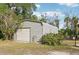 Metal detached garage with a roll-up door, surrounded by greenery and a chain-link fence at 7415 36Th E Ave, Palmetto, FL 34221