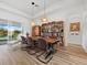 Bright dining room featuring a wood table, chandelier, and a built-in bookshelf, next to lake views through sliding glass doors at 8284 Barton Farms Blvd, Sarasota, FL 34240