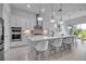 A modern, all-white kitchen features an island with pendant lighting and stainless steel appliances at 8541 Coastal Palms Gln, Parrish, FL 34219