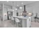 A modern, all-white kitchen features an island with pendant lighting and stainless steel appliances at 8541 Coastal Palms Gln, Parrish, FL 34219