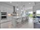 A modern, all-white kitchen features an island with pendant lighting and stainless steel appliances at 8541 Coastal Palms Gln, Parrish, FL 34219