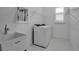 Functional laundry room with utility sink, washer and dryer, and storage shelves at 8541 Coastal Palms Gln, Parrish, FL 34219