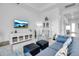 Bright living room features a blue sofa, decor cabinet, stylish chairs and large TV for relaxing and entertainment at 8541 Coastal Palms Gln, Parrish, FL 34219