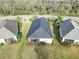 An aerial view of homes with dark roofs, screened porches, and serene grassy areas, bordered by foliage at 11231 Woodlake Way, Parrish, FL 34219