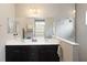 Bathroom featuring double sinks, a dark vanity, a large mirror, and walk-in shower with neutral tile at 11231 Woodlake Way, Parrish, FL 34219