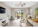 Sun-filled living room boasting wood-look tile, modern furnishings, and sliding glass doors to a screened lanai at 11231 Woodlake Way, Parrish, FL 34219