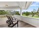 Inviting porch with wooden floors, white railing, and comfortable Adirondack chairs overlooking a green lawn at 3783 Beneva Oaks Blvd, Sarasota, FL 34238