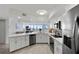 Bright kitchen with white cabinets, stainless appliances, stone counters, and seamless transition into living space at 5279 Isla Key S Blvd # 113, St Petersburg, FL 33715