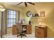 Bright home office features a wooden desk, neutral chair, large windows, and a ceiling fan at 5974 San Michelle Dr, Sarasota, FL 34243